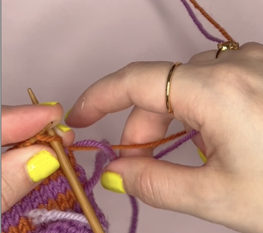 wrapping the purple yarn over the top of the orange yarn