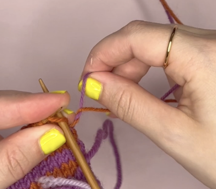 wrapping the purple yarn under the orange yarn